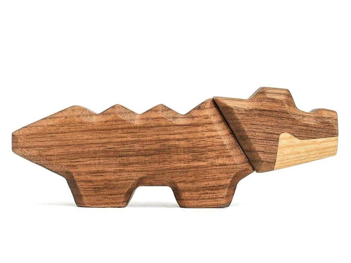Et trælegetøj formet som en stiliseret krokodille eller alligator med geometriske vinkler og et enkelt, minimalistisk design.