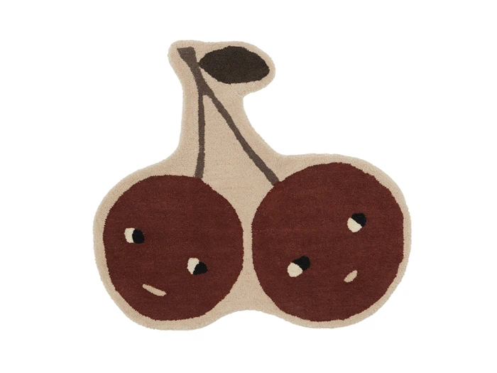 Et beige tæppe formet som to kirsebær med brune frugter, hvor hvert kirsebær har et enkelt, abstrakt ansigt og deler en fælles stilk med et mørkt blad.