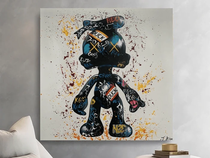 Et farverigt graffiti-maleri af en tegneseriefigur med ord og symboler over hele kroppen hænger på en lysegrå væg over en sofa.