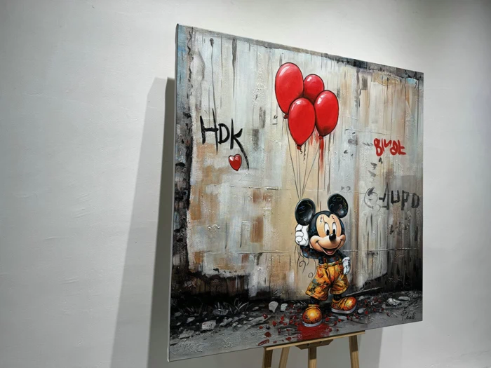 Et maleri af Mickey Mouse, der holder tre røde balloner og står foran en væg dækket af graffiti med bogstaverne HDK og et hjerte på.