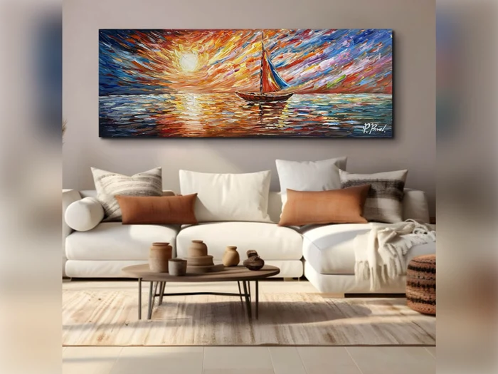 En stue med en hvid sofa, brune puder, et rundt sofabord med keramik og et farverigt maleri af en sejlbåd ved solnedgang på væggen over sofaen.