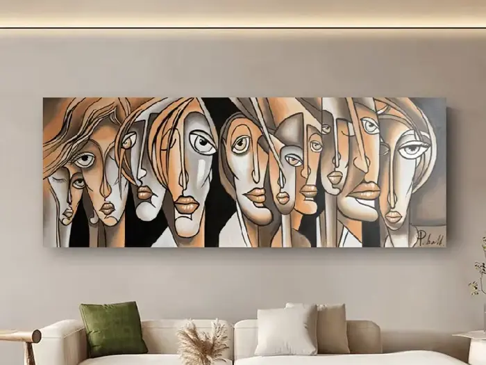 Et moderne abstrakt maleri af langstrakte ansigter med udtryksfulde øjne i neutrale toner hænger over en beige sofa med grønne og hvide puder i en stilfuld stue.