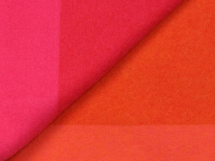 Et nærbillede af to overlappende stoffer, det ene lyserødt og det andet orange, der viser deres bløde tekstur og levende farver.