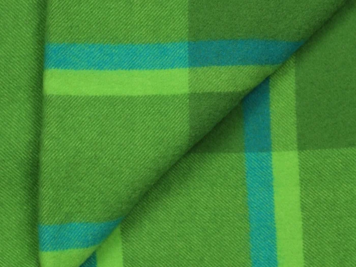 Nærbillede af grønt og blåt ternet stof med krydsende linjer og et pænt foldet hjørne.