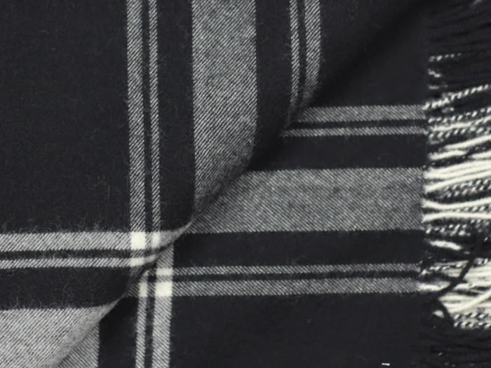 Nærbillede af et sort og hvidt ternet stof med frynsede kanter og krydsende linjer, der danner et ternet mønster.