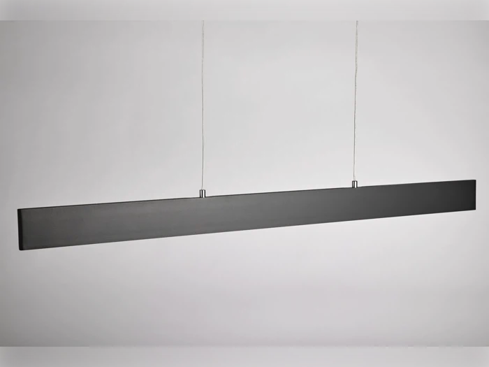En moderne, minimalistisk sort lineær pendel hænger ned fra loftet i to tynde ledninger mod en almindelig hvid baggrund.