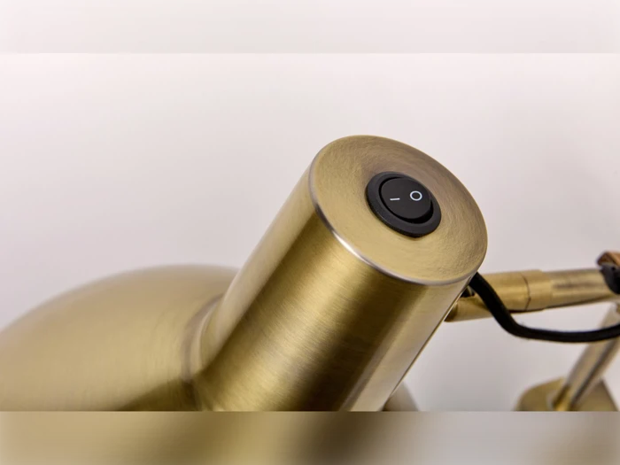 Nærbillede af en messingfarvet lampe med en sort tænd/sluk-knap på toppen, med I- og O-symboler.