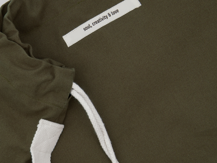 Nærbillede af en olivengrøn stofpose med hvide snore og en hvid etiket, hvor der står soul, creativity & love.