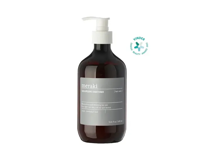 En brun pumpeflaske med Meraki Volumising Conditioner med en grå etiket ved siden af et grønt Winner Beauty Award-badge.