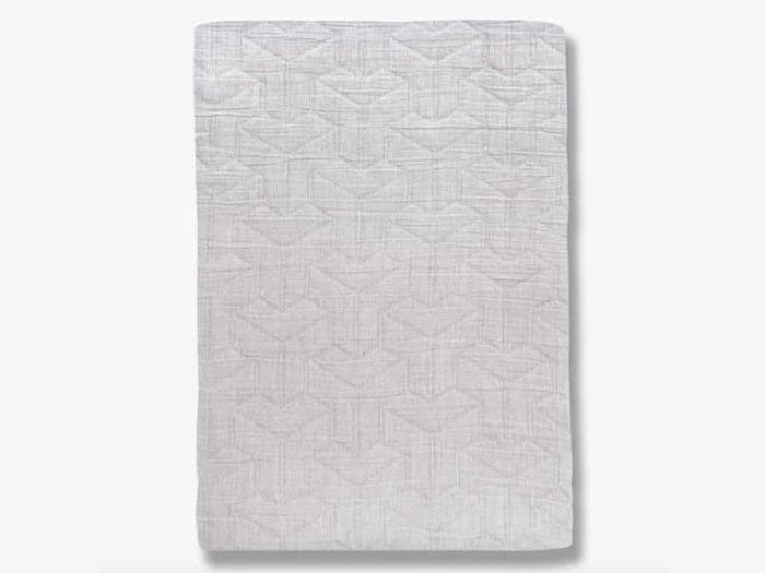 Et foldet lysegråt tæppe med et subtilt geometrisk mønster, der vises lodret mod en almindelig hvid baggrund.