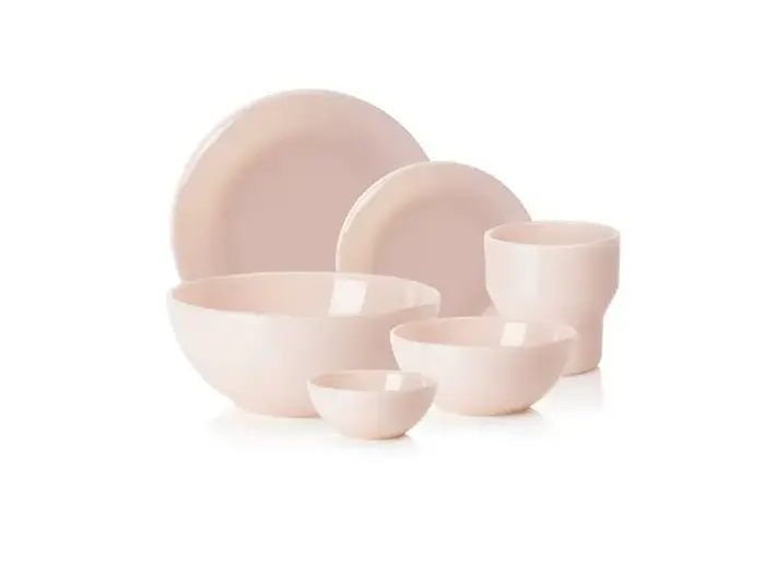 Et sæt med seks lyserøde keramikfade, bl.a. tallerkener, skåle og en kop, arrangeret på en hvid baggrund.