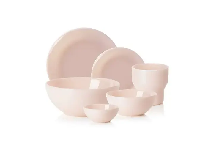 Et sæt med seks lyserøde keramikfade, herunder to tallerkener, tre skåle i forskellige størrelser og en kop, arrangeret på en hvid baggrund.