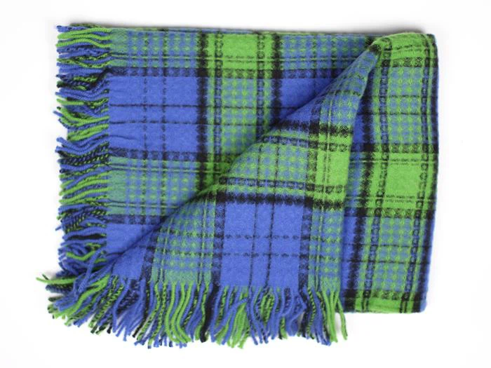 Et foldet uldtæppe med blåt og grønt ternet mønster og frynser på kanterne, vist på en hvid baggrund.