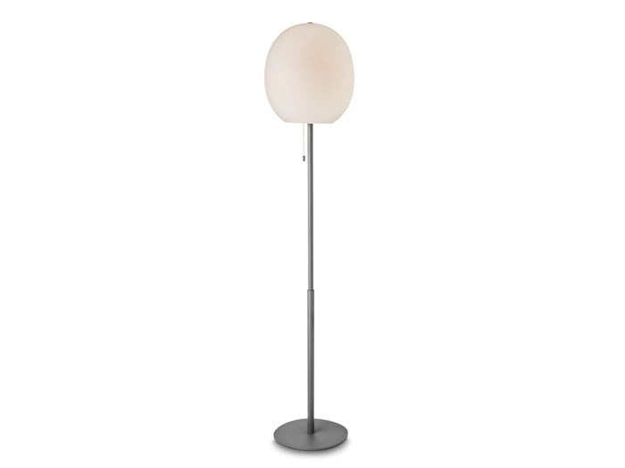 En moderne gulvlampe med en rund, hvid lampeskærm, en slank sølvfarvet stang og en cirkulær fod på en almindelig hvid baggrund.