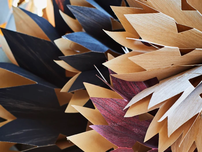 Nærbillede af lagdelte, takkede papirformer i brune, sorte og vinrøde nuancer, der skaber et abstrakt, struktureret mønster.