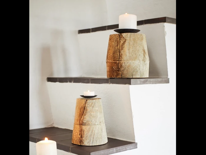 To hvide stearinlys står i rustikke træholdere på trinene af en hvid trappe med mørkebrune kanter; et andet stearinlys står på det nederste trin.