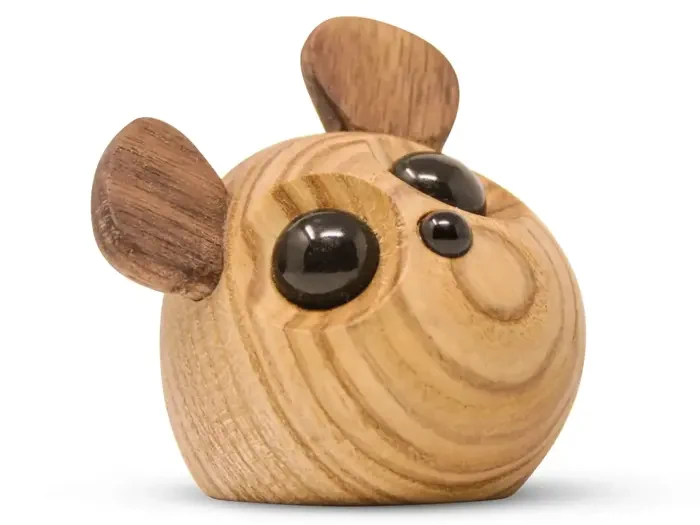 En lille, rund træskulptur af et hundehoved med store sorte øjne og opretstående ører, udskåret i lyst og mørkt træ.