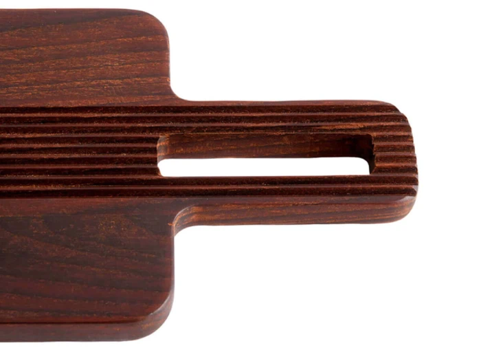 Nærbillede af et mørkt skærebræt af træ med en rektangulær åbning i håndtaget på en hvid baggrund.