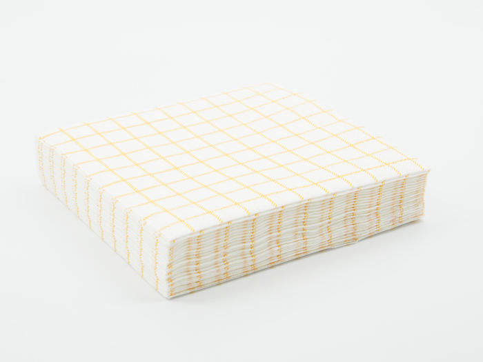 En stak hvide papirservietter med et gult gittermønster, pænt arrangeret på en almindelig hvid baggrund.
