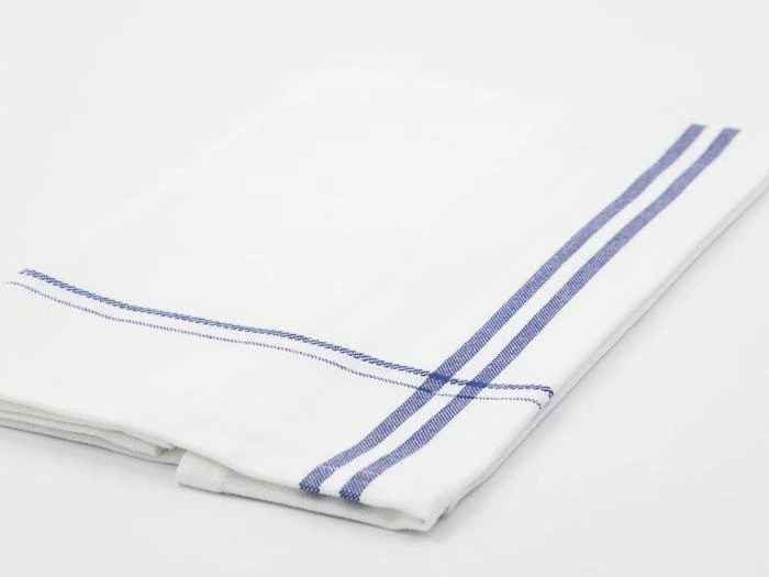 En pænt foldet hvid stofserviet med to parallelle blå striber langs kanten, placeret på en almindelig hvid overflade.
