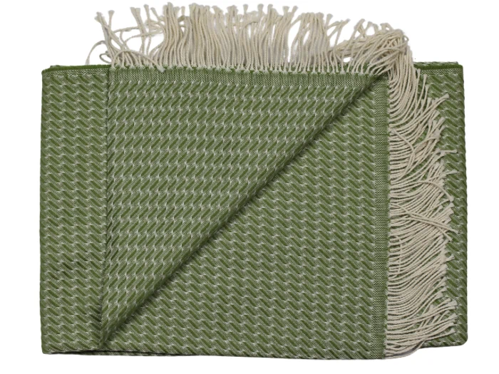 Et foldet grønt vævet tæppe med cremefarvede frynser i enderne, der viser et struktureret zigzagmønster og sirligt arrangerede kanter.