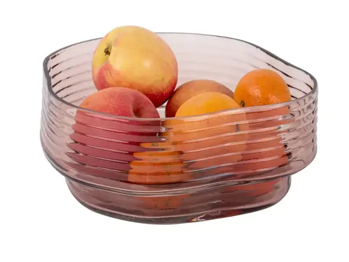 En klar, riflet glasskål med æbler og appelsiner på en hvid baggrund.