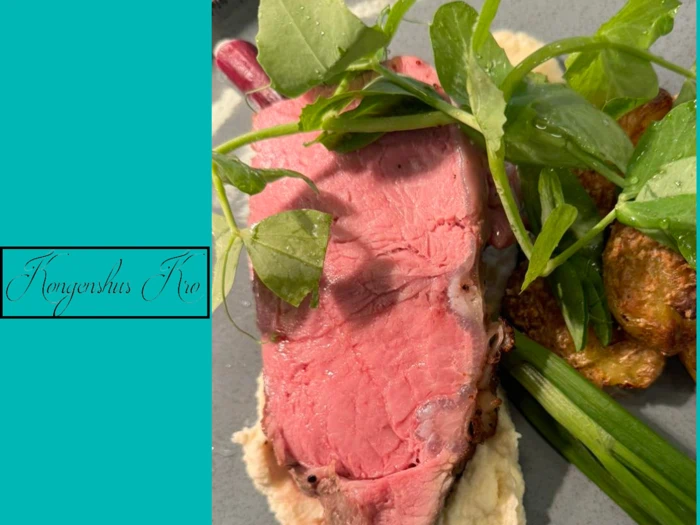 En tallerken med en tyk skive roastbeef, sprøde kartofler, grønne løg, bladgrønt og cremet puré på et gråt fad, ved siden af en blågrøn tekst, hvor der står Konversation Trio.