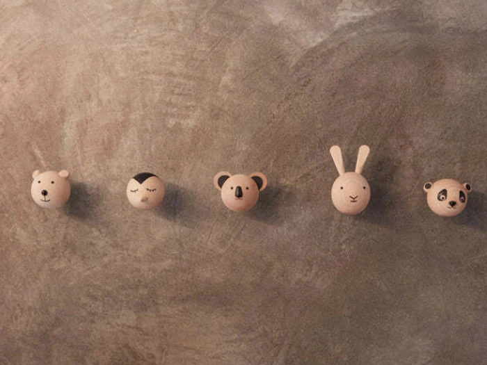 Fem runde træknager formet som søde dyreansigter - en bjørn, en kat, en koala, en kanin og en panda - på en struktureret grå væg.