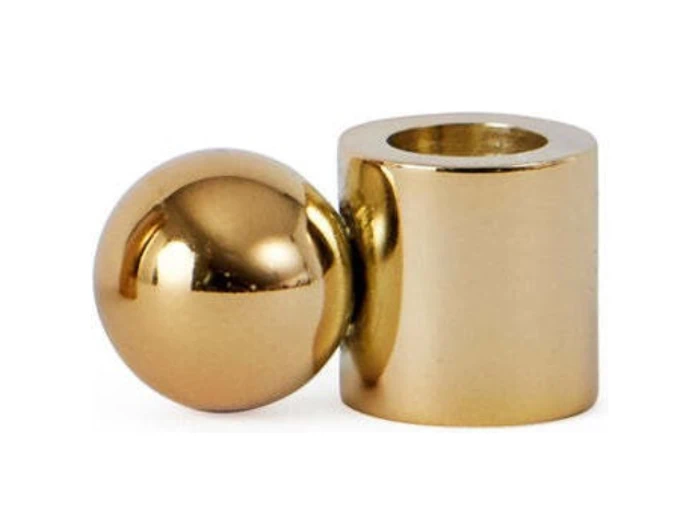 En skinnende guldkugle og en matchende guldcylinder med en hul midte er placeret side om side på en hvid baggrund.