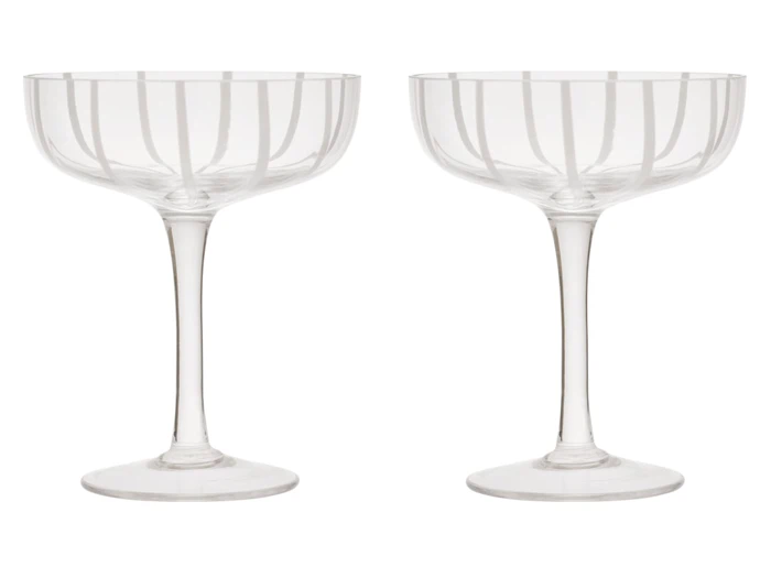 To champagneglas i klart glas i coupé-form med ætsede lodrette linjer, der står side om side på en hvid baggrund.