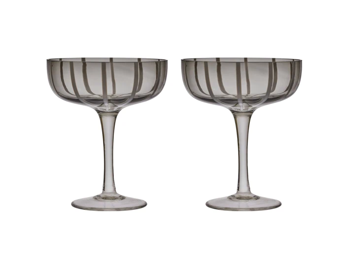 To klare coupéglas med stilk og lodrette striber, der står side om side på en hvid baggrund.