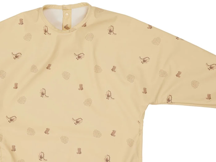 Langærmet, beige børnesmock med små brune dyre- og planteprint, med trykknaplukning bagpå tæt på kraven.