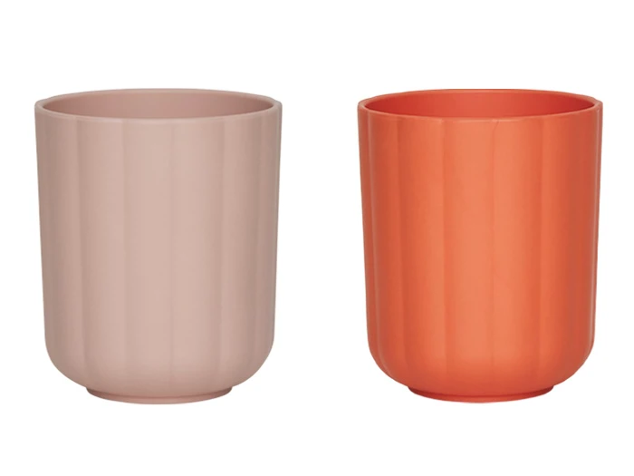To ribbede, cylindriske kopper, der er afbildet side om side; den ene er lyserød, og den anden er orange. Begge har en mat overflade og ingen hank.