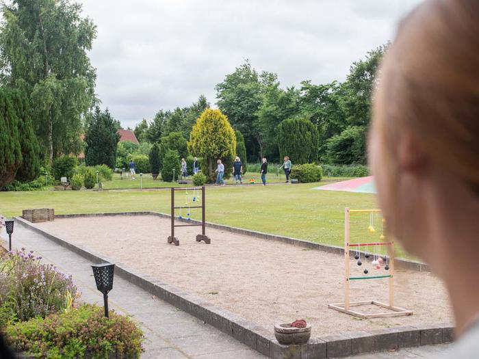 En person observerer en have med spil og flere mennesker, der går i det fjerne på en overskyet dag.