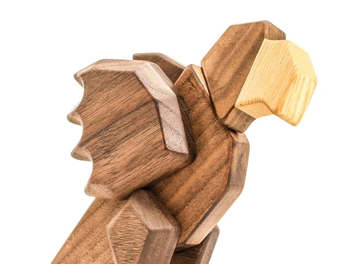 En træskulptur af et brølende løvehoved, fremstillet af glatte, kantede stykker med en lysere træfarve til mundområdet.