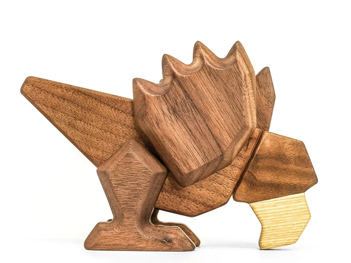 Et trælegetøj formet som en stiliseret dinosaur med kantede træk, lavet af forskellige nuancer af træ, på en hvid baggrund.