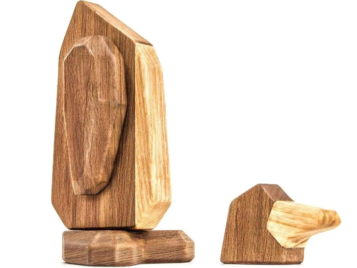 To minimalistiske træskulpturer, der ligner abstrakte pingviner, en der står oprejst og en, der ser ud til at ligge ned, lavet af forskellige nuancer af poleret træ.