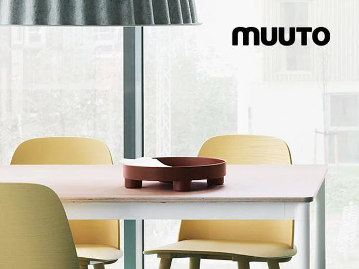 Et moderne spiseområde med gule stole, et hvidt bord, en rød bakke og store vinduer. Ordet MUUTO står i øverste højre hjørne.