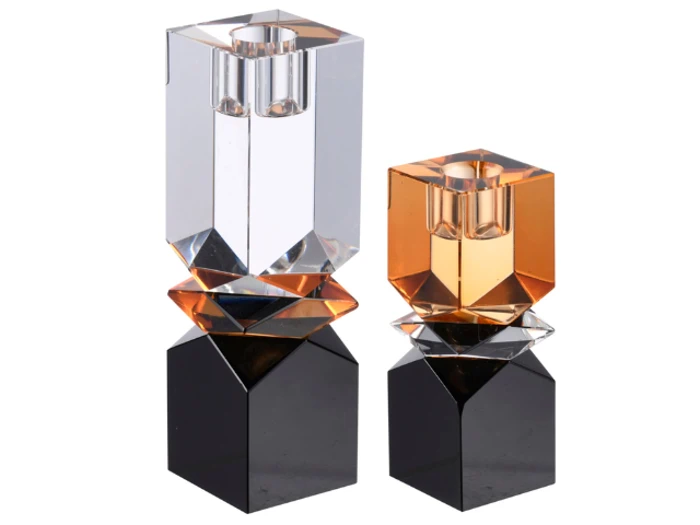 To geometriske, flerfarvede lysestager med klare, ravfarvede og sorte sektioner, hver med facetterede overflader og et moderne, kantet design.