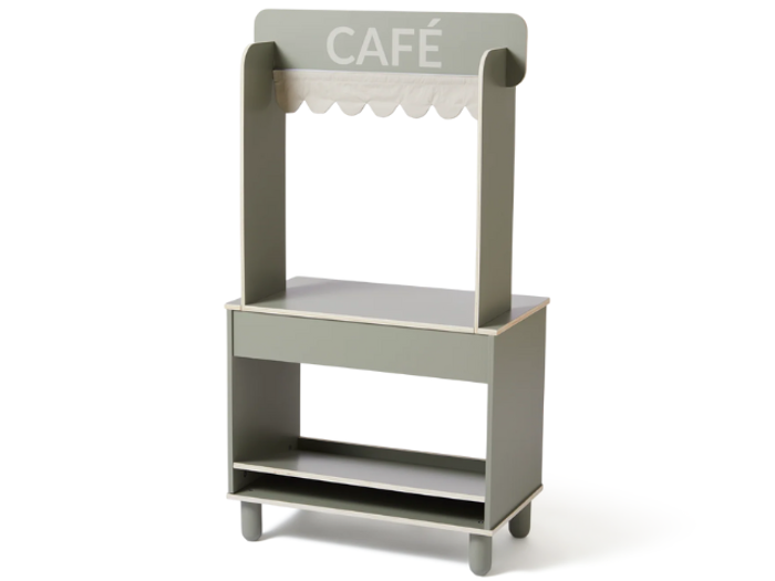Et lille, lysegrønt legecaféstativ af træ med en bølget hvid markise og ordet CAFÉ på toppen. Den har hylder og en disk.