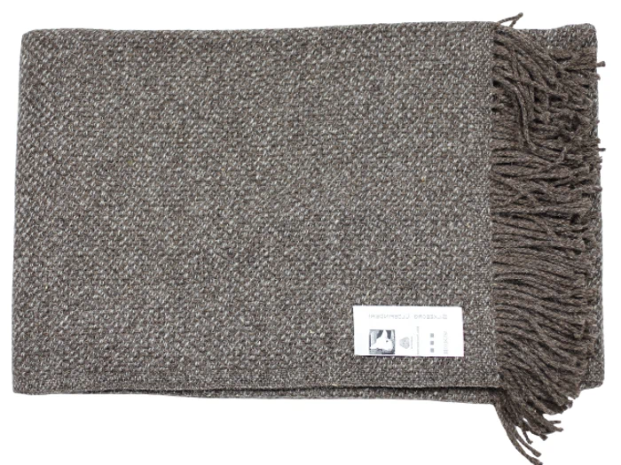 Et foldet brunt vævet tæppe med frynser i den ene ende og en hvid etiket påsat.