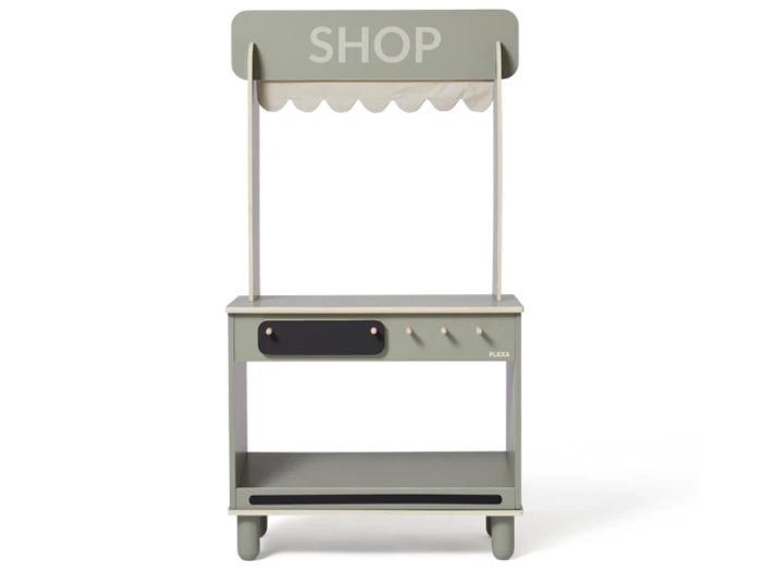 En lille, lysegrøn legebutik i træ med baldakin, disk, tre knopper, et kridttavleskilt og en hylde nedenunder. Ordet SHOP er trykt øverst.
