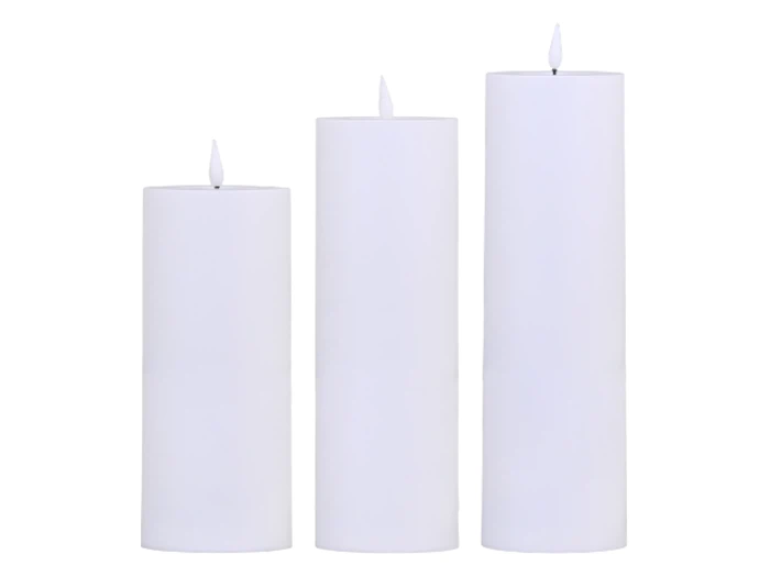 Tre hvide bloklys i forskellige højder med små flammer, anbragt side om side på en hvid baggrund.