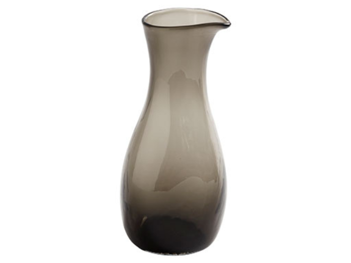 En høj, røggrå glaskande med smal hals, bred bund og en lille tud på en hvid baggrund.