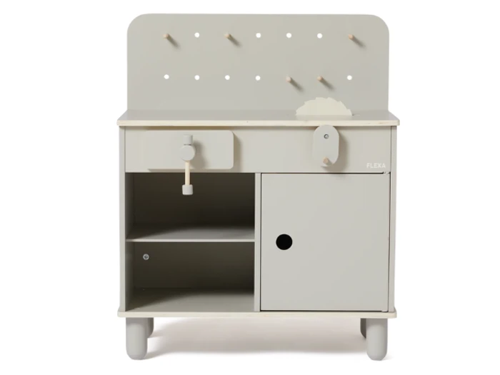 Et lille, lysegråt legekøkken i træ med åbne hylder, en skuffe, en dør og knager på bagpanelet.