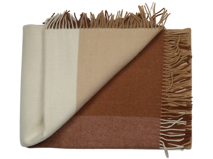 Et foldet, frynset tæppe med et farveblokmønster i creme, beige og brune toner, der viser både for- og bagside.