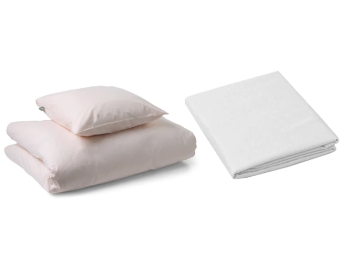 En foldet lyserød dyne med en matchende pude ligger ved siden af et pænt foldet hvidt lagen på en almindelig hvid baggrund.