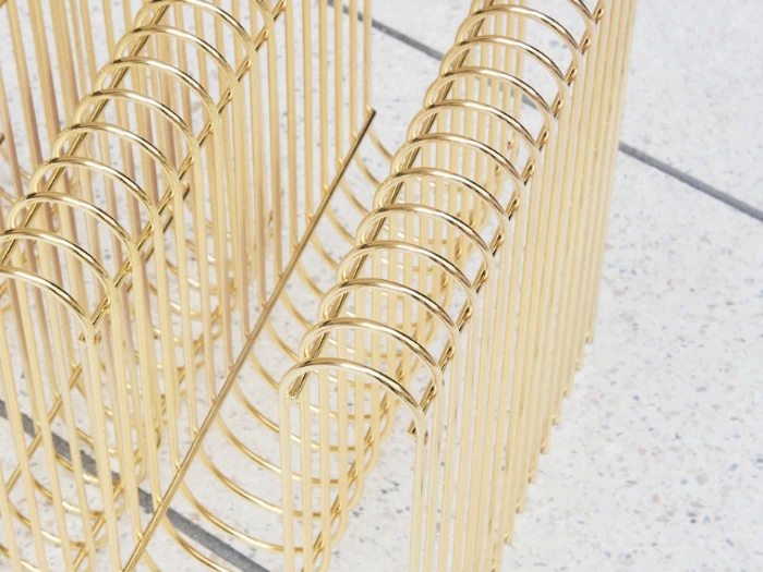 Nærbillede af to guldfarvede metalstativer med buede, parallelle stænger på en spættet hvid overflade.
