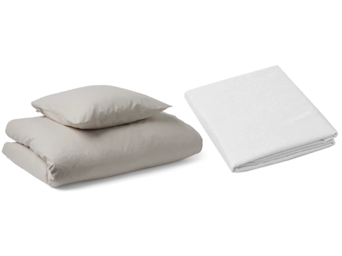 Et sæt pænt foldet beigefarvet sengetøj med to puder ovenpå, ved siden af et separat foldet hvidt lagen på en almindelig hvid baggrund.