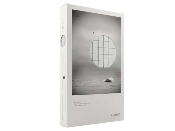 Minimalistisk emballage viser et havlandskab i gråtoner med fugle, en hval og et cirkulært gitteroverlay; teksten i bunden lyder by NORD.